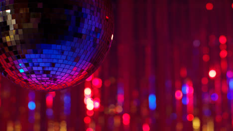 Nahaufnahme-Einer-Rotierenden-Spiegelkugel-In-Einem-Nachtclub-Oder-Einer-Disco-Mit-Blinkendem-Stroboskoplicht-Und-Funkelnden-Lichtern-Im-Hintergrund-1